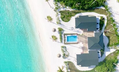 Aerial view of a Beach Residence at Joy Island Maldives featuring a private pool, wooden deck, multiple roof sections, and direct access to the white sand beach and turquoise lagoon