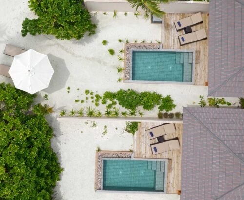 Aerial view of Beach Pool Villas at Brennia Kottefaru Maldives showing private rectangular pools, wooden decks with sun loungers, and surrounding white sand and tropical greenery