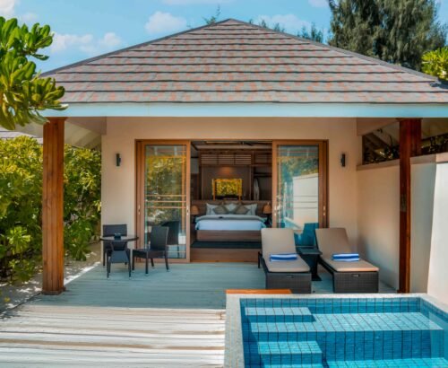 Beach Pool Villa at Brennia Kottefaru Maldives featuring a private blue-tiled pool, wooden deck with sun loungers, and open sliding doors leading into the bedroom