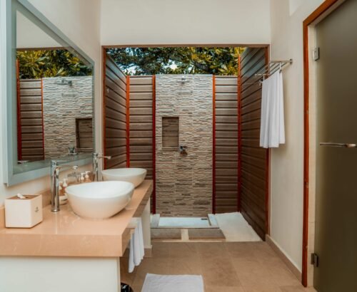 Modern Beach Villa bathroom at Brennia Kottefaru Maldives with dual sinks and an open-air shower space