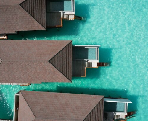 Aerial view of Deluxe Water Pool Villas at Brennia Kottefaru Maldives with private rectangular pools extending over the clear turquoise lagoon
