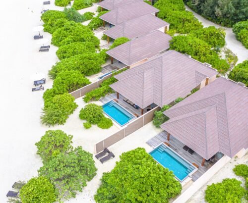 Aerial view of Two Bedroom Beach Pool Residences at Brennia Kottefaru Maldives featuring private rectangular pools, wooden decks, and tropical greenery next to the white sand beach