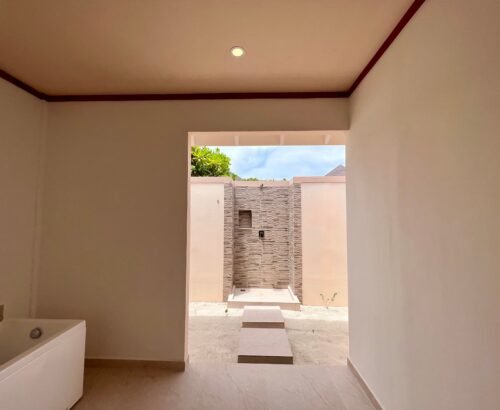 Bathroom in a Two Bedroom Beach Pool Residence at Brennia Kottefaru Maldives featuring a white bathtub and an open outdoor stone-tiled shower under natural light