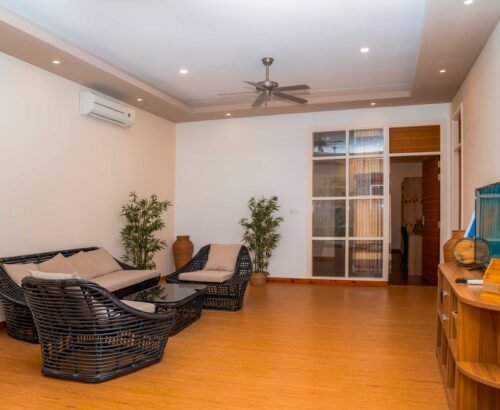 Bright living area in a Two Bedroom Bougain Villa at Brennia Kottefaru Maldives featuring rattan sofa and chairs, coffee table, indoor plants, and warm wooden flooring